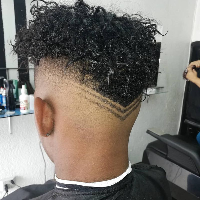 Curly top with a hair design carved into the fade